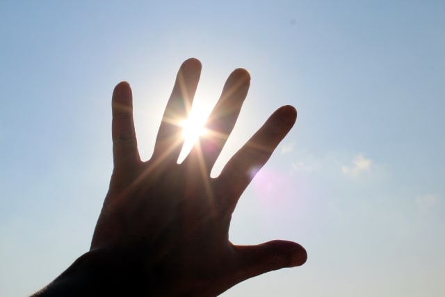 キラキラ輝く太陽に手をかざす
